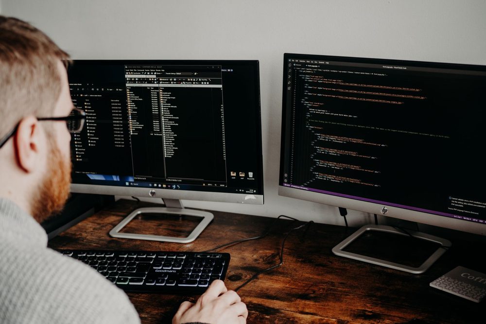Medewerker van een webbureau werkt aan meerdere schermen